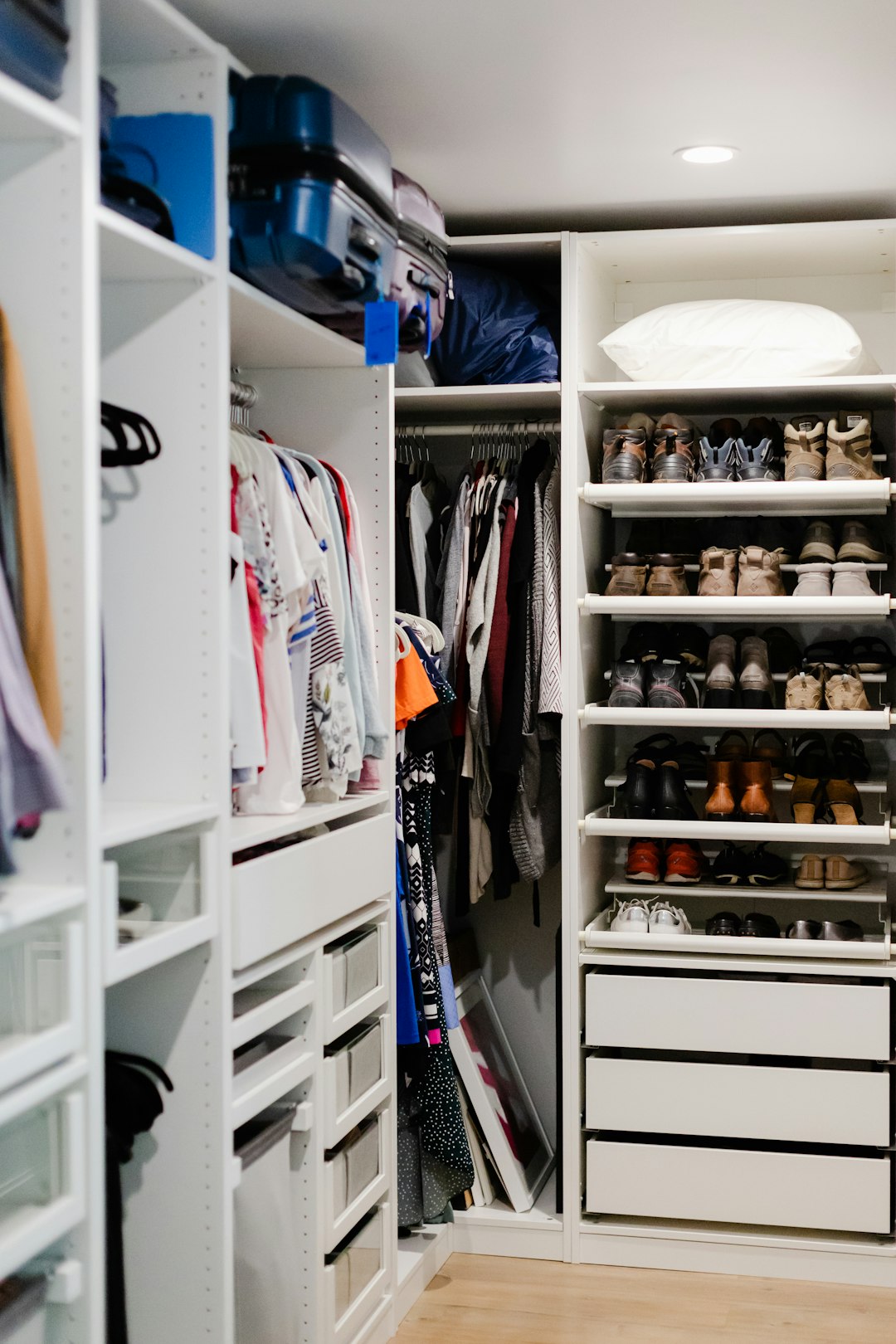 A modern, white closet with open shelving, drawers, and a rack for clothes & footwears.